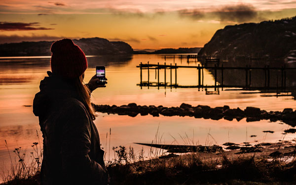 person som tar en bild av havet vid solnedgången